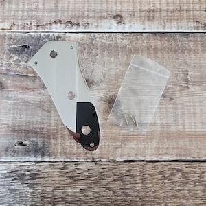 Puede incluir: Un golpeador de guitarra cromado con tres agujeros de montaje y una cubierta de plástico negro. El golpeador se empaqueta con cuatro tornillos pequeños en una bolsa de plástico transparente.