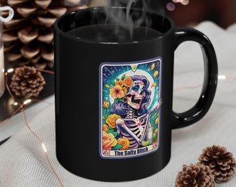 May include: Black coffee mug with a colorful illustration of a skeleton woman with flowers in her hair and the text "The Salty Bitch".