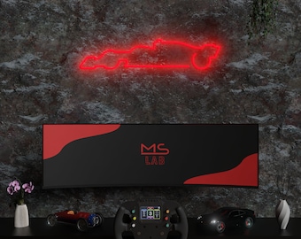 May include: A red neon sign in the shape of a race car is mounted on a dark, textured wall. Below, a black display with the text "MS LAB" sits above a shelf with a racing wheel, model cars, and decorative vases.
