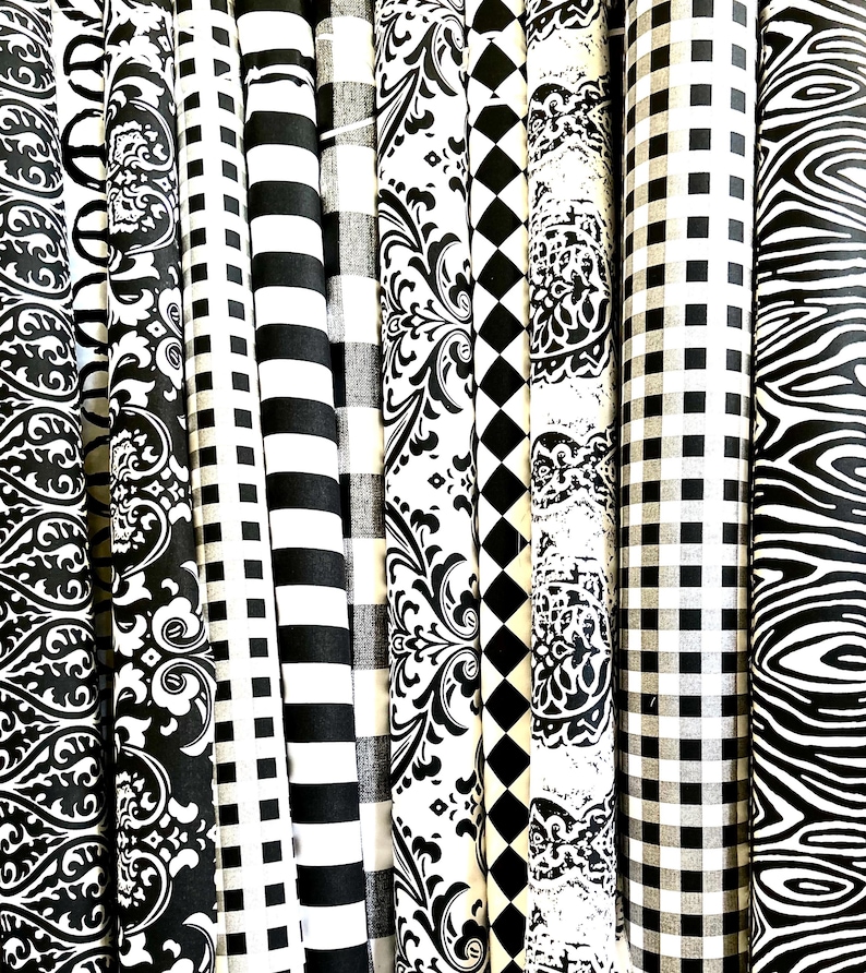 Pu&ograve; includere: Una collezione di rotoli di tessuto con vari motivi in bianco e nero. I disegni includono strisce, quadri, damasco e rombi. I tessuti sono arrotolati strettamente, mostrando le diverse trame e stili.