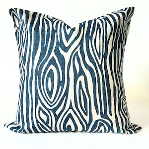 May include: Square decorative pillow with a navy blue and white zebra stripe pattern. The pillow has a soft, textured appearance and is likely made of fabric. The design features organic, flowing lines, creating a visually appealing accent piece.