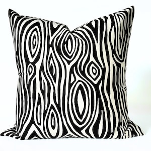 May include: Square decorative pillow with a black and white wood grain pattern. The pillow features a repeating design of organic, swirling lines and oval shapes, creating a bold, graphic statement. The pillow is a square shape.