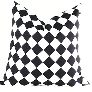 May include: A square decorative pillow with a black and white checkered pattern. The pillow has a soft, plush appearance and is designed to be used as a decorative accent on a bed or sofa. The pillow's pattern is a classic design.