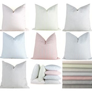 May include: Nine decorative throw pillows in various colors, each with vertical stripe patterns. Colors include white, green, blue, and red. The pillows are arranged in a grid, with a stack of pillows and fabric swatches also shown.