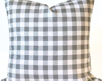 May include: Square throw pillow with a gray and white gingham pattern. The pillow has a soft, textured appearance and is designed for decorative use on a sofa or bed. The pillow's classic design adds a touch of farmhouse style to any room.
