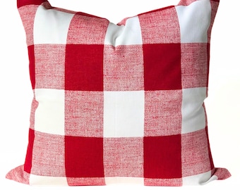 May include: Square decorative pillow with a red and white buffalo check pattern. The pillow has a soft, textured appearance and is designed for home decor. The bold color scheme adds a rustic touch to any living space.