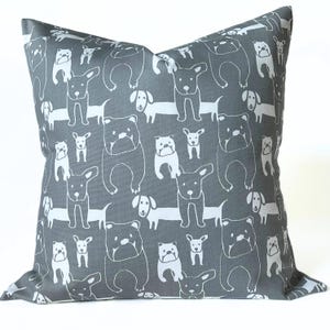 May include: Gray decorative pillow with a repeating white line drawing pattern of various dog breeds. The dogs are in different poses and sizes, creating a playful and whimsical design. The pillow is square-shaped.