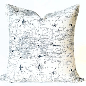 Pu&ograve; includere: Un cuscino quadrato con un design a mappa del mondo. Il cuscino presenta uno sfondo bianco con una mappa dettagliata in bianco e nero, bussole e aeroplani. Il testo "THE WORLD" &egrave; visibile. Questo cuscino decorativo &egrave; perfetto per gli appassionati di viaggi.