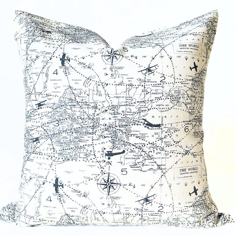 Pu&ograve; includere: Un cuscino quadrato con un design a mappa del mondo. Il cuscino presenta uno sfondo bianco con una mappa dettagliata in bianco e nero, bussole e aeroplani. Il testo "THE WORLD" &egrave; visibile. Questo cuscino decorativo &egrave; perfetto per gli appassionati di viaggi.