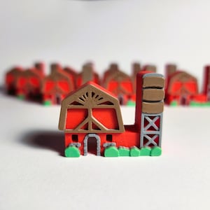 May include: A red barn with a brown roof and a brown silo. The barn has a white door and a white window. The silo has a gray ladder. The barn and silo are surrounded by green grass.