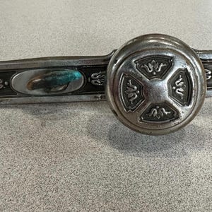 May include: A silver door knob with a decorative design and a keyhole. The knob is attached to a silver plate with a decorative design.