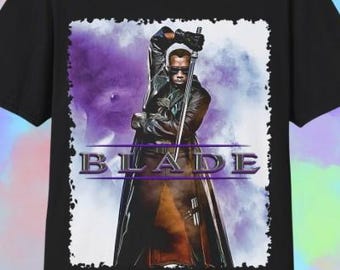 May include: Black t-shirt with a graphic of the character Blade, wielding a sword. The design includes a purple and white backdrop and the word "BLADE". The t-shirt has a crew neck.