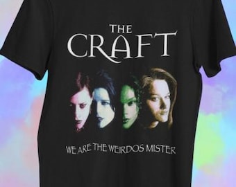 Könnte beinhalten: Schwarzes T-Shirt mit dem weißen Schriftzug "THE CRAFT" über vier Gesichtern. Darunter steht der Text "WE ARE THE WEIRDOS MISTER". Die Gesichter haben unterschiedliche Haut- und Haarfarben.