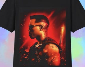 May include: Black t-shirt with a striking graphic of a man in profile, wearing sunglasses, set against a red backdrop. The design includes a sword and detailed artwork, creating a dynamic and bold image.