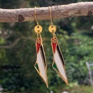 May include: Gold earrings shaped like the outline of Israel, with the colors of the Israeli flag: blue, white, and green. The earrings have a red star of David at the top.