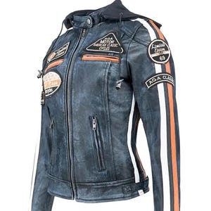 Puede incluir: Chaqueta de moto de cuero azul desgastado con capucha negra y rayas blancas y naranjas en las mangas. La chaqueta presenta múltiples parches con texto, incluyendo "AGA MOTOR AMERICAN CLASSIC CYCLES" y "AGA CLASS".