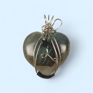 May include: A white ceramic mug with a black handle and the text "But First, Coffee" in a bold, black font. The mug is set against a blurred background, suggesting a cozy setting.