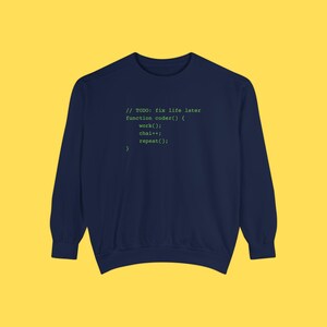 A dark blue crewneck sweatshirt featuring green programming text centered on the chest against a solid yellow background.