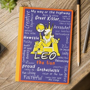 Puede incluir: Un cuaderno con una cubierta morada que presenta una ilustración de un león de dibujos animados y la palabra "LEO". El diseño incluye texto que describe los rasgos de personalidad de Leo, con un borde naranja y un fondo de madera.