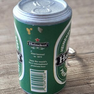 May include: Miniature green Heineken beer can with silver top and pull tab. The can features the Heineken logo and text, including "First brewed in 1873" and "Now the world's No.1 international premium beer."