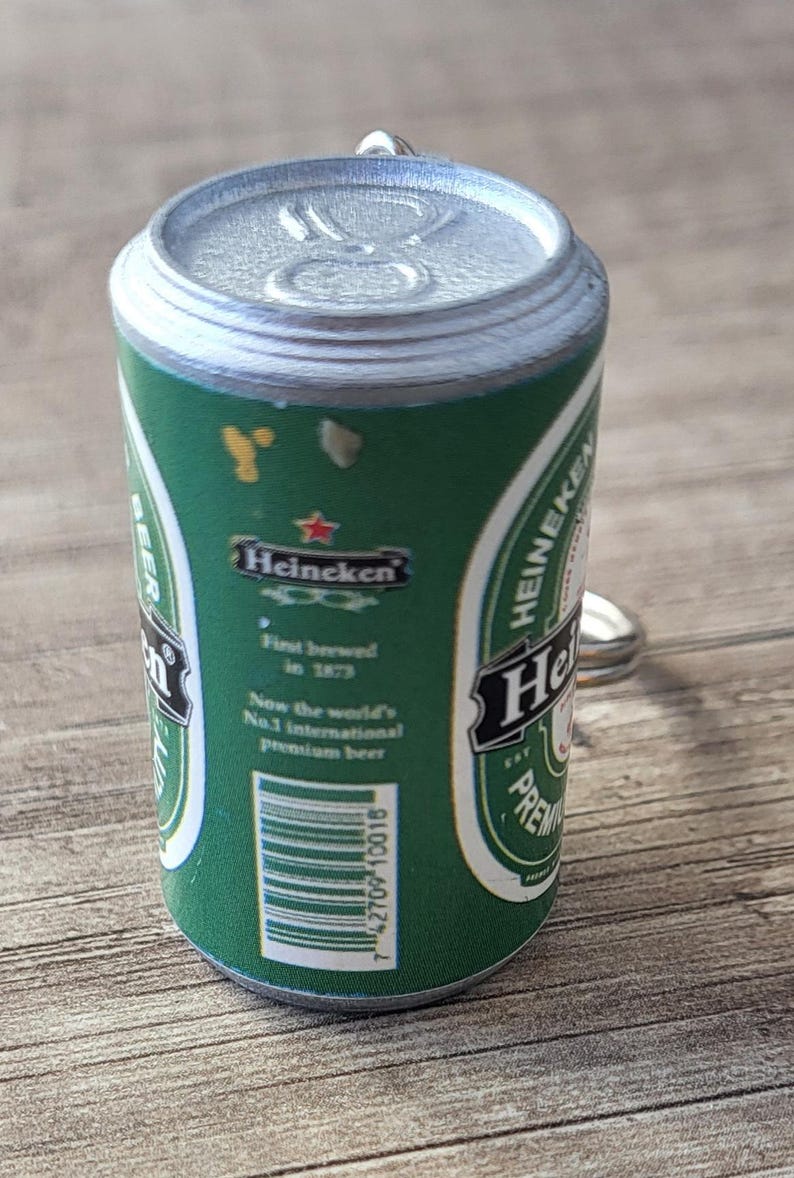 May include: Miniature green Heineken beer can with silver top and pull tab. The can features the Heineken logo and text, including "First brewed in 1873" and "Now the world's No.1 international premium beer."