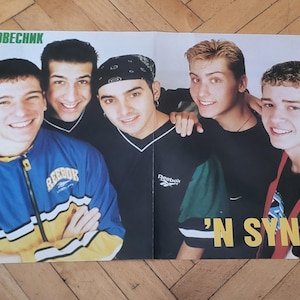 May include: A magazine spread featuring the boy band *NSYNC. The group of five young men are smiling at the camera. One member wears a blue and yellow jacket. The text "'N SYNC" is visible in yellow and green.