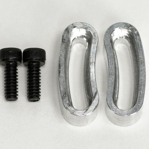 May include: Two silver metal rings with a rounded oval shape and a smooth, textured surface. Two black screws are included.