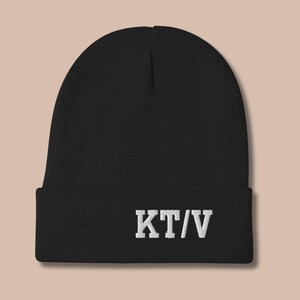 May include: Black knit beanie with a white embroidered logo that says "KT/V".