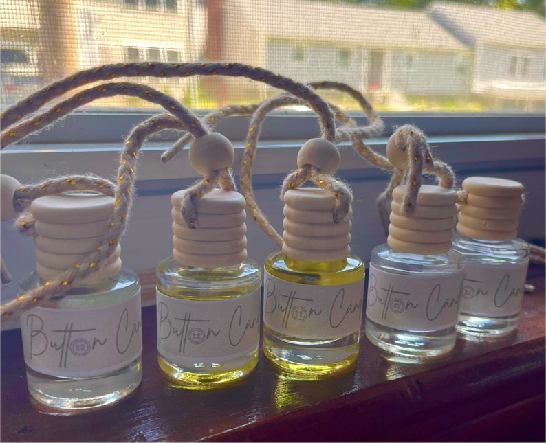 Pu&ograve; includere: Cinque bottiglie di vetro trasparente con tappi di legno e uno spago dorato che pende da esse. Ogni bottiglia ha un'etichetta bianca con la scritta "Button Car" stampata su di essa.