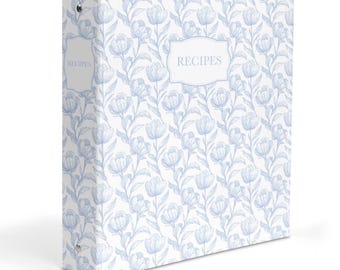 May include: A three-ring binder featuring a light blue and white floral pattern. The front cover displays a decorative label frame with the word RECIPES printed in the center. A matching label frame with the word RECIPES is also on the spine.