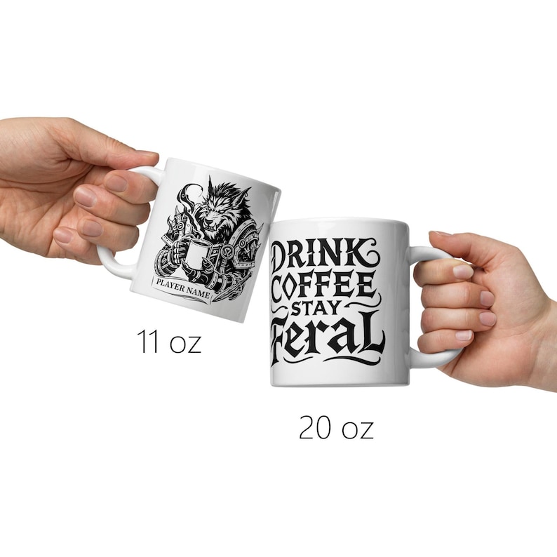 K&ouml;nnte beinhalten: Zwei wei&szlig;e Keramikbecher. Ein Becher zeigt eine Schwarz-Wei&szlig;-Illustration eines Werwolfs, der einen Becher h&auml;lt, mit dem Text "PLAYER NAME". Der andere Becher hat den Text "DRINK COFFEE STAY FERAL" in Schwarz. Ein Becher ist 312 ml, der andere 567 ml.