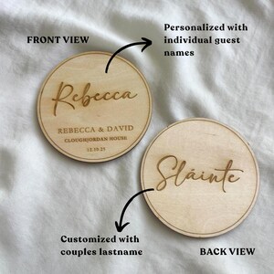 May include: Two round wooden coasters. One coaster is engraved with the name "Rebecca" and wedding details. The other coaster is engraved with the word "Sláinte". The coasters are personalized with guest names and couples' last names.