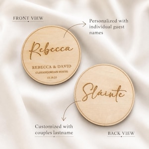 May include: Two circular light-coloured wooden discs. The front view disc features the engraved name Rebecca, the text REBECCA & DAVID, CLOUGHJORDAN HOUSE, and 12.10.25. The back view disc features the engraved word Slainte in script lettering.