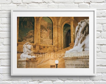 May include: A white marble lion statue with a detailed mane, sitting on a stone pedestal with the inscription "In honor of the Twentieth Massachusetts and in memory of..." The statue is in a grand building with arched doorways and painted murals.