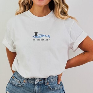May include: White t-shirt with a blue and white fish wearing a top hat and the text "SOFISHICATED" printed on the front.