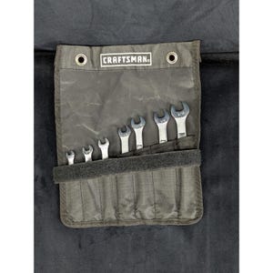 May include: A dark gray canvas tool roll with the "CRAFTSMAN" logo, holding six open-end wrenches. The wrenches are silver and vary in size. The roll has a velcro closure and two metal grommets at the top.