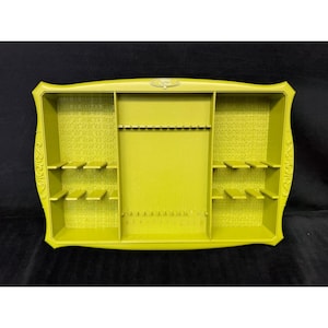 May include: A lime green jewelry organizer with multiple compartments and shelves. The organizer has a rectangular shape with decorative edges and a textured interior. It features a central section with slots and side compartments with small shelves.