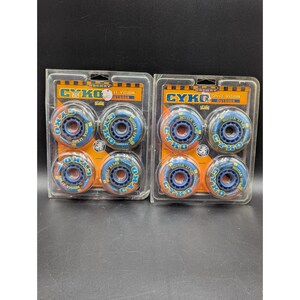 May include: Two sealed plastic blister packs containing four blue and orange inline hockey wheels each. The packaging features the text CYKO SPLIT VISION OUTDOOR HOCKEY. The wheels have a blue center hub and an orange outer rim with blue lettering.