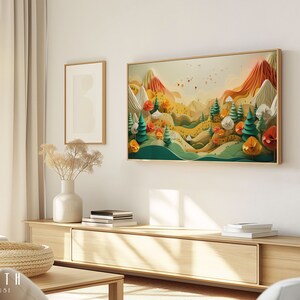 May include: A framed print of a colourful paper art landscape with mountains, trees, and flowers. The print is hanging on a white wall in a living room setting.