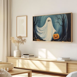 Op de afbeelding: Een witte geest die een uitgeholde pompoenlamp in een donker bos draagt. Het schilderij is in goud gelijst en hangt aan een witte muur.
