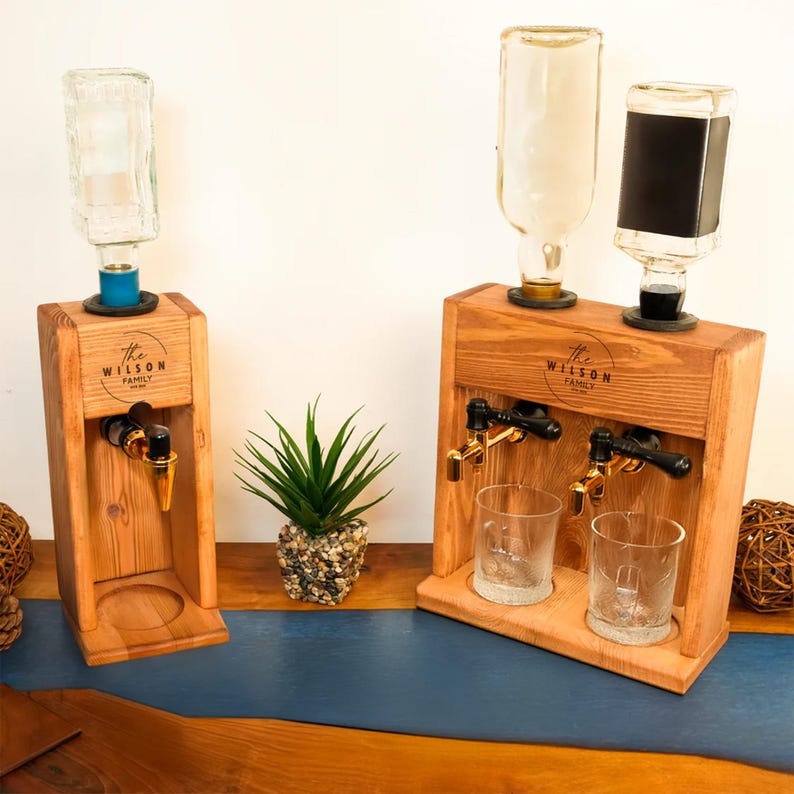 two wooden dispensers, each with a glass bottle and two glass cups, placed on a wooden surface.
