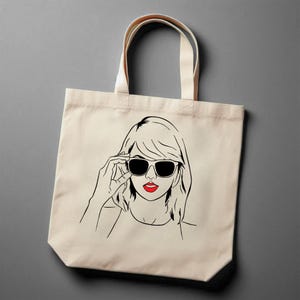 May include: A white canvas tote bag with a black line drawing of a woman wearing sunglasses and red lipstick.