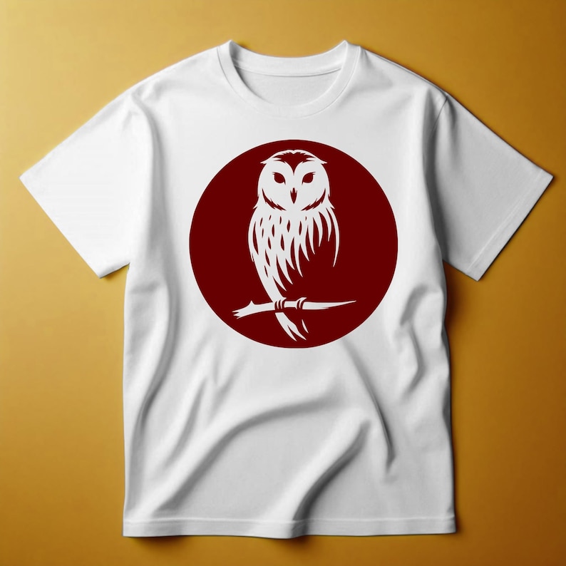 Op de afbeelding: Wit T-shirt met een rode cirkelvormige afbeelding van een witte uil die op een tak zit.