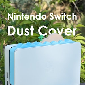 Op de afbeelding: Witte stofkap voor Nintendo Switch met een blauw golfontwerp en een klein eiland met een palmboom erop. De kap heeft het Nintendo Switch logo aan de voorkant.