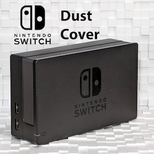 Puede incluir: Funda antipolvo negra para la consola Nintendo Switch con el logotipo de Nintendo Switch en la parte superior y dos puertos USB en el lateral.