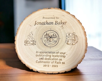 May include: A wooden plaque with a compass, campfire, and backpack design. The plaque reads "Presented to: Jonathan Baker In appreciation of your outstanding leadership and dedication as Cubmaster of Pack 66 2013-2023"
