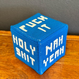 May include: A blue, cube-shaped decorative item with white text that reads "FUCK IT", "HOLY SHIT", and "MAH YEAH". The item is made of a textured material and sits on a wooden surface. The logo "fox creations" is visible.