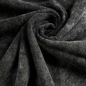 May include: Close-up of a dark grey fabric with a textured surface. The fabric is folded and draped, creating a soft and inviting look.