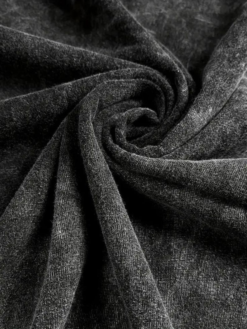 May include: Close-up of a dark grey fabric with a textured surface. The fabric is folded and draped, creating a soft and inviting look.