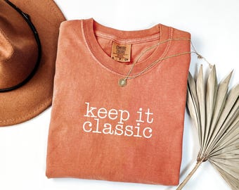 May include: A coral-colored t-shirt with the text "keep it classic" printed in white. The shirt is made of a soft, comfortable fabric and has a relaxed fit.